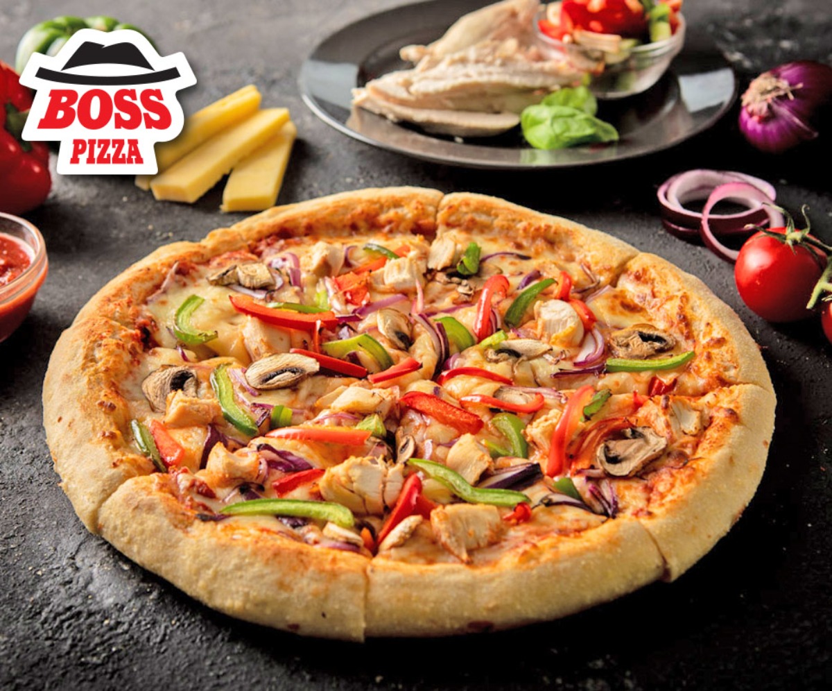 Boss pizza topped with peppers, mushrooms and chicken, sliced and presernted with various toppings around the pizza