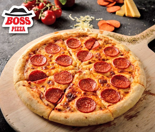 Our pepperoni heaven pizza on a wooden board with ingredients to the pizza surrounding the board